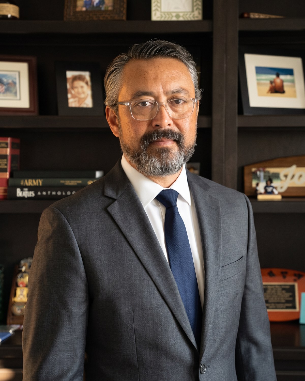 Elton Johnson, Kentucky-licensed attorney, in his Elizabethtown office. Charcoal suit, navy tie, bookshelf with family photos and military mementos visible behind him.
